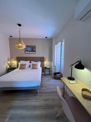 une chambre avec un lit blanc et un bureau dans l'établissement Maison La Citre, à Port-Vendres