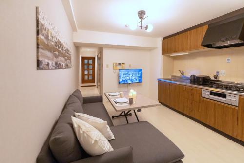 a living room with a couch and a table at Dotonbori East Residence Haru - Self Check-In Only in Osaka