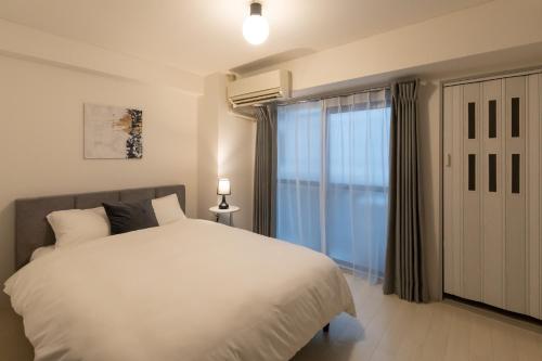 a bedroom with a white bed and a window at Dotonbori East Residence Haru - Self Check-In Only in Osaka