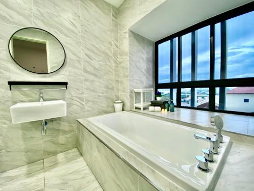 une salle de bain avec une baignoire, un lavabo et un miroir dans l'établissement MW Imperio Residence Studio Suites with Private Bath tub, à Malacca