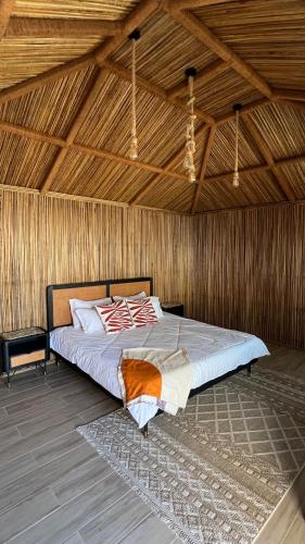 a bed in a room with a wooden ceiling at Qantab Hut in Muscat
