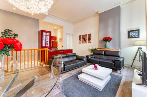Elle comprend un salon doté d'un mobilier en cuir noir et d'un lustre. dans l'établissement Magnifique Appartement au Cœur du Quartier Historique Saint-Michel, à Bordeaux