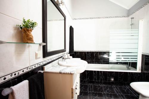 a black and white bathroom with a sink and a tub at Villa Margarida in Ponta do Sol