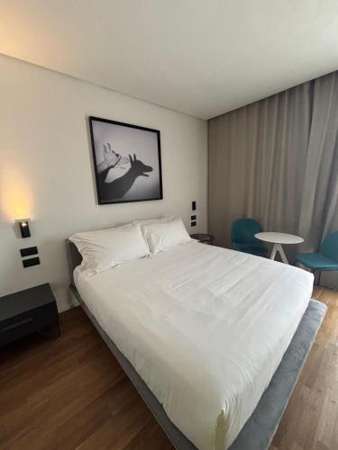 a bedroom with a large white bed and blue chairs at MòN Luxury Rooms SPA in Nicolosi