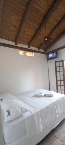 a bedroom with a white bed with two towels on it at Pousada Prumirim Surf Suítes in Ubatuba