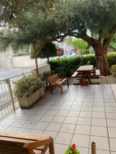 a patio with benches and tables and a tree at Appartamento al mare - Marotta in Marotta