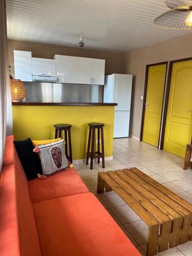 a living room with a couch and a kitchen at Appartement Cayenne Chic Design Élégant en Bois Tropical in Cayenne