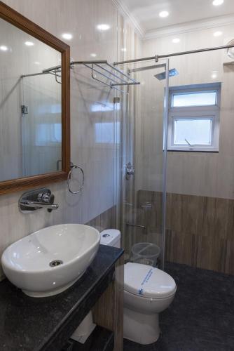 a bathroom with a sink and a toilet and a shower at Pool View Studio Apartment in Candolim Beach Resort in Baga