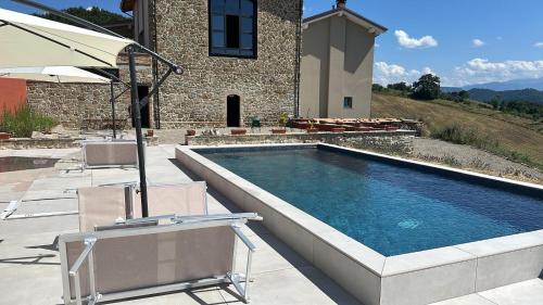 a swimming pool with two chairs and an umbrella at Fuoridicampo beige in Roncovetro