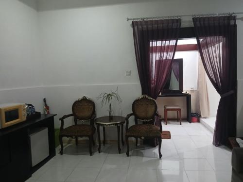 ein Wohnzimmer mit Stühlen und einem Tisch und einem Fernseher in der Unterkunft Villa Pool Private and Romantic In Kuta Bali in Kuta