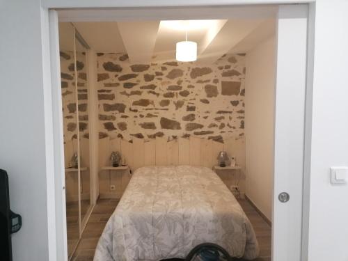 une chambre avec un lit et un mur en pierre dans l'établissement La Cigale, à La Ciotat