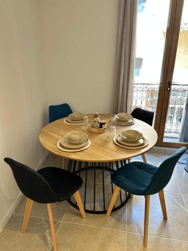 - une table en bois avec des chaises et des assiettes dans l'établissement Appartement centre-ville Bedarieux, à Bédarieux
