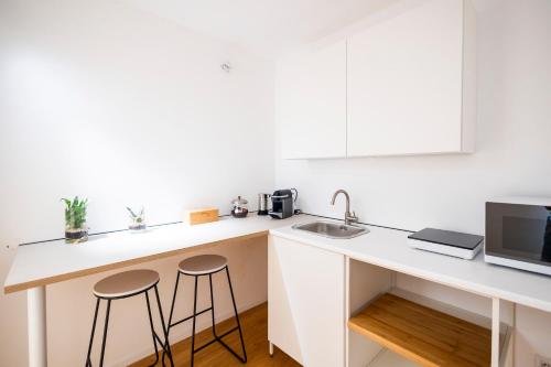 a white kitchen with a sink and two stools at Caveau in Palermo