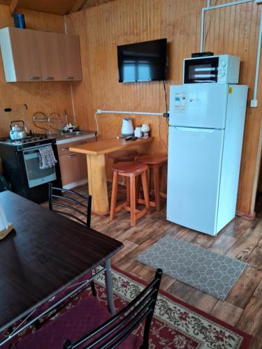a kitchen with a white refrigerator and a table at Cabaña Cubero in Hualaihué