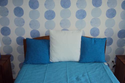 Una cama con almohadas azules y blancas en un dormitorio en Odeceixe Beach Apartments, en Odeceixe