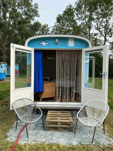 a rv with two chairs and a table and a bench at Het Huis van Bewustzijn in Limmen