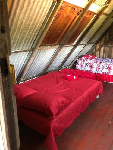 a room with two red beds in a attic at Chalé Maison Blanche in Maracanã