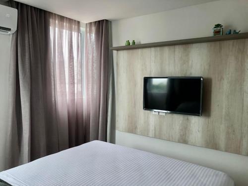 a bedroom with a bed and a tv on a wall at Urban Janeiro - Bessa in Tambaú