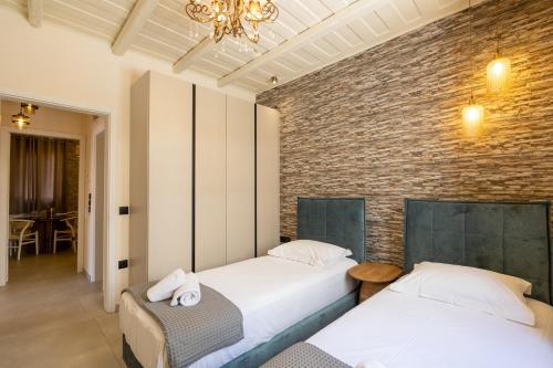 two beds in a room with a brick wall at ARCHONTIKO 1922 in Argostoli