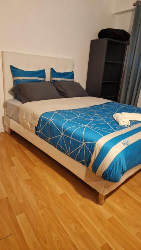 - un lit avec des draps bleus et blancs et du parquet dans l'établissement Appartement lumineux en duplex avec terrasse et jardin, à Vaujours
