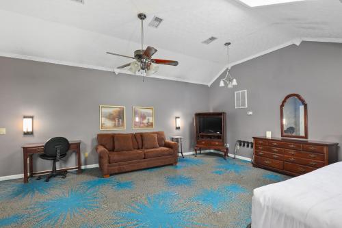 a bedroom with a bed and a couch and a ceiling fan at Four Seasons Country Inn in Glasgow