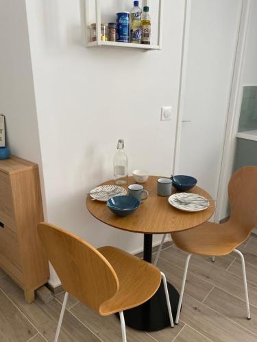 a wooden table with two chairs and bowls on it at Studio centre ville proche RER A wifi in Saint-Germain-en-Laye
