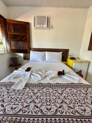 a bed with two white towels and two roses on it at Mar à Vista Ilha de Boipeba in Ilha de Boipeba