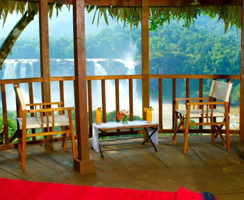 a porch with two chairs and a table with a view at Rainforest Resort in Athirappilly