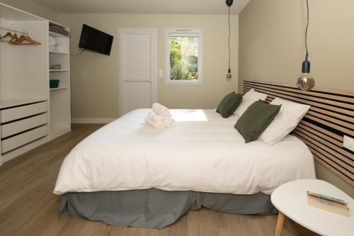 une chambre avec un grand lit blanc dans une pièce dans l'établissement L Arberet 2 village, 4 étoiles, à Vendays-Montalivet