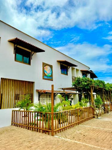 a white building with a fence in front of it at Parcel do Gostoso Pousada in São Miguel do Gostoso