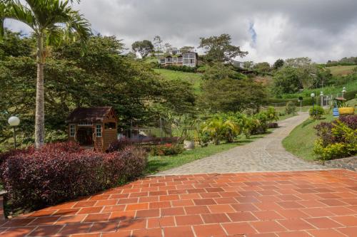 a brick path in a garden with a house on a hill at Lago Calima - Bella Finca in Madroñal