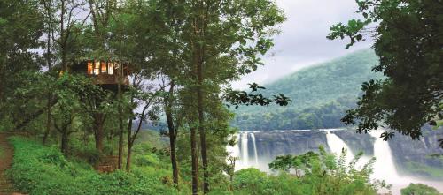 a tree house in the middle of a waterfall at Rainforest Resort in Athirappilly