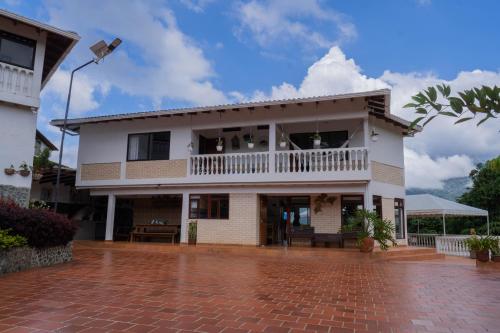 a white house with a balcony and a brick driveway at Lago Calima - Bella Finca in Madroñal