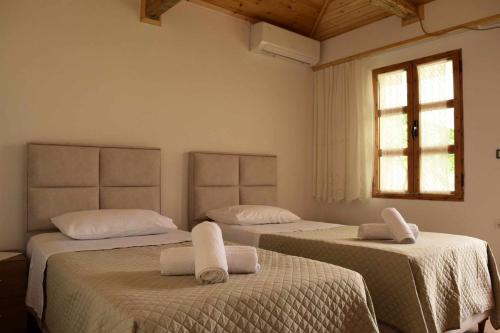 a bedroom with two beds with white sheets and a window at Sokaku i te Marreve GuestHouse in Gjirokastër