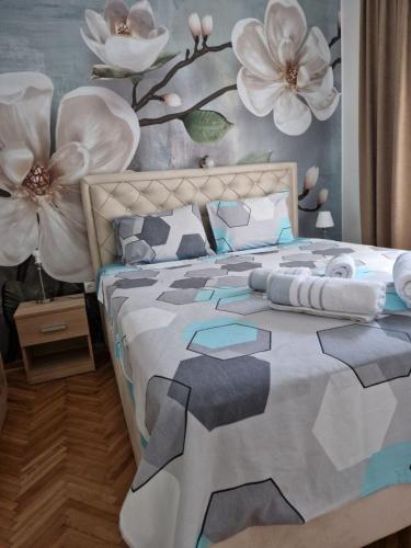 a bedroom with a bed with flowers on the wall at Apartment Holiday in Vrnjačka Banja