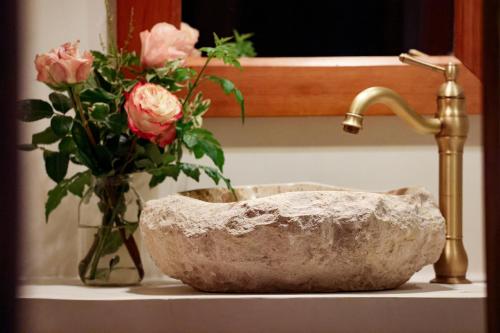 a stone sink with a vase of pink roses at Mukima Manor in Nanyuki