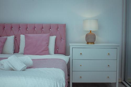 a bed with a pink headboard next to a dresser at kanambwa House Kilamba in Camama