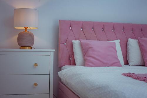 a bed with a pink headboard and a lamp on a dresser at kanambwa House Kilamba in Camama