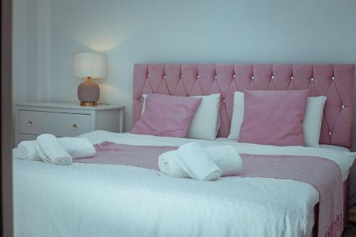 a bedroom with a bed with pink and white pillows at kanambwa House Kilamba in Camama