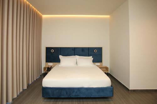 a bedroom with a bed with white sheets and pillows at ReiVal Hotel Marina Vlore in Vlorë