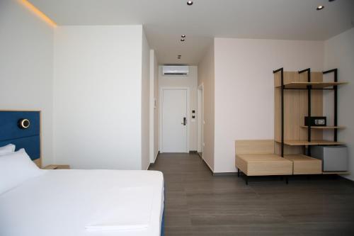 a bedroom with a white bed and a wooden shelf at ReiVal Hotel Marina Vlore in Vlorë