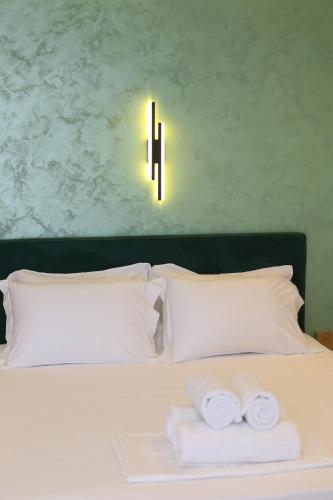 a bed with white pillows and a light on the wall at ReiVal Hotel Marina Vlore in Vlorë