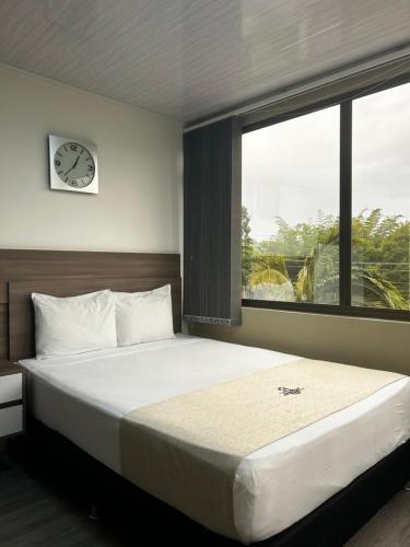 a bedroom with a large bed with a clock on the wall at Hotel Campo Real in Rionegro