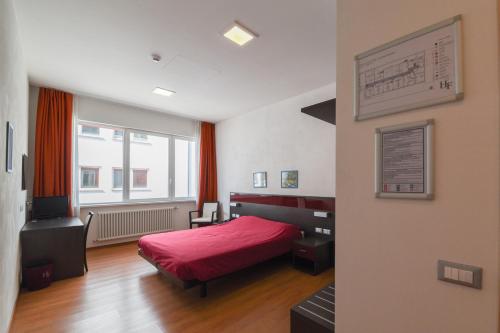 a bedroom with a red bed and a window at Hotel Fiera in Bolzano