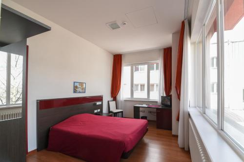 a bedroom with a red bed and a desk at Hotel Fiera in Bolzano