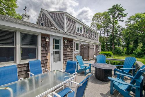 a patio with blue chairs and a table at Game Room Walk to Nantucket Sound in Chatham