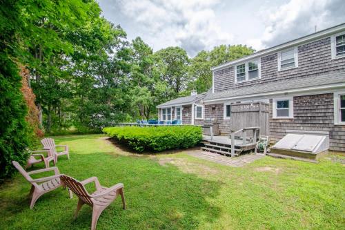 a yard with two chairs and a house at Game Room Walk to Nantucket Sound in Chatham