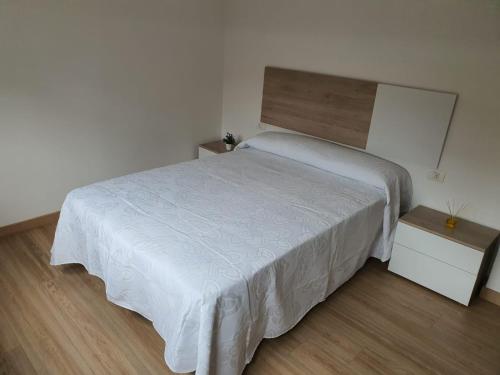 a bedroom with a white bed and a wooden floor at Sol in Cangas de Morrazo