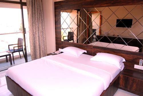 a bedroom with a large bed with a large mirror at Hotel Apaar in Diu