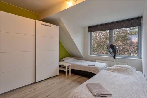 a small bedroom with two beds and a window at Duplex appartement in rustige woonwijk in Mortsel